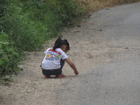 鄉(xiāng)村道路邊撿石子的女孩