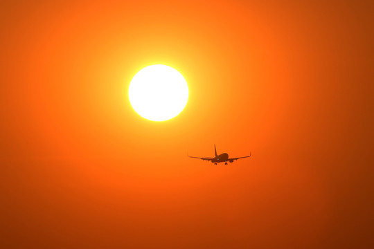 夕陽(yáng)晚霞中降落的飛機(jī)