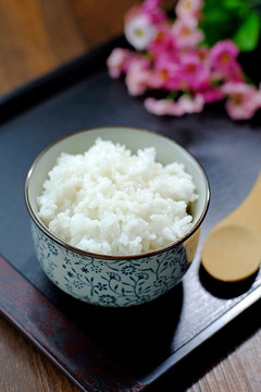 青花碗中的米飯和木勺放在托盤中