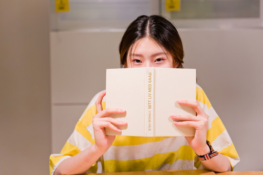 用書遮臉的女生