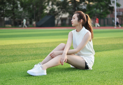 坐在校園操場上的美女大學(xué)生