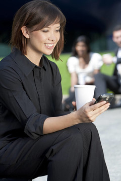 美麗的亞洲年輕女人發(fā)短信和喝咖啡