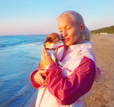 年輕的女人和她的狗在海灘上