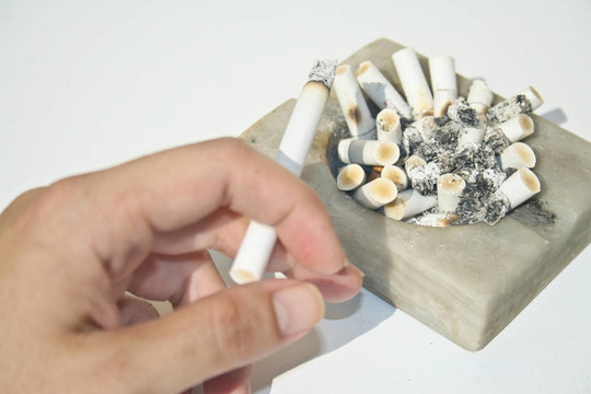 滿煙灰缸，手拿著香煙
