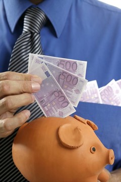 商人在存錢(qián)罐里插入歐元紙幣