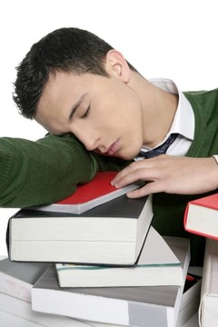 男學生在書桌上堆書睡覺