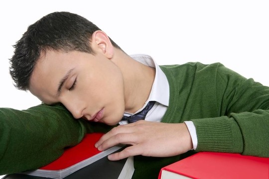 男學生在書桌上堆書睡覺