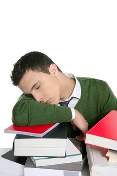 男學生在書桌上堆書睡覺