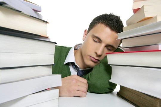 男學(xué)生在書桌上堆書睡覺