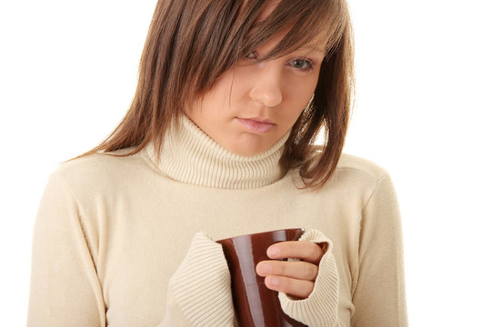 一個(gè)漂亮的女孩拿著一杯熱飲料