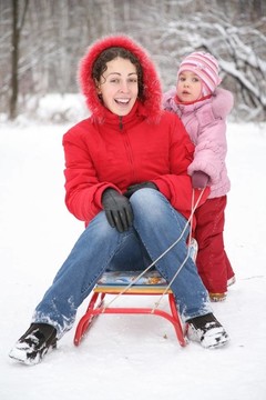 冬天，媽媽和孩子坐在公園的雪橇上