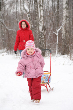 冬天孩子帶雪橇和媽媽在公園