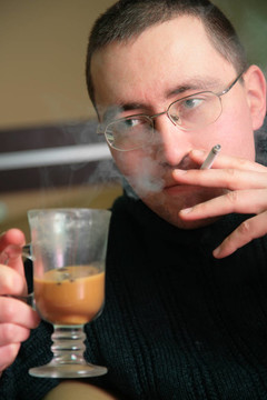 男人喝一杯酒和一支香煙