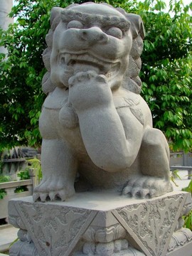 頑皮的中國(guó)獅雕像舔它的爪子