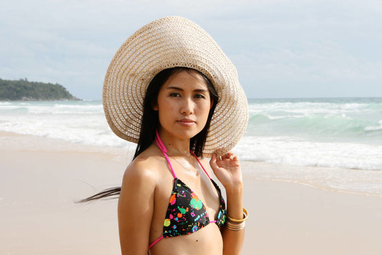在海灘上，在一個明亮的比基尼美麗的亞洲女子。