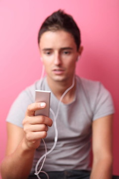 年輕英俊的男人在他的便攜式MP3播放器在自己的房間里聽音樂