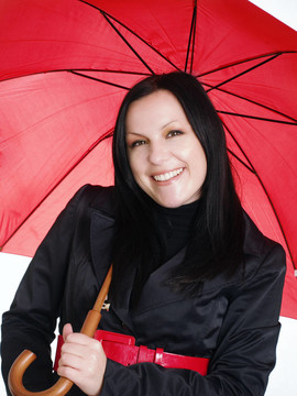 微笑的黑發(fā)女人在秋天；防雨的衣服打著傘