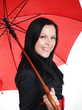 微笑的黑發(fā)女人在秋天；防雨的衣服打著傘