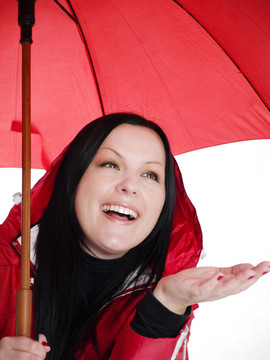 微笑的黑發(fā)女人在秋天；防雨的衣服打著傘