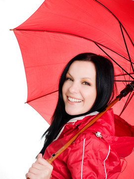微笑的黑發(fā)女人在秋天；防雨的衣服打著傘