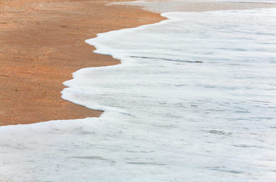 海岸沙灘上的海浪泡沫