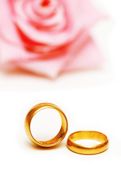 兩個金色的結(jié)婚戒指和一朵粉紅色的玫瑰