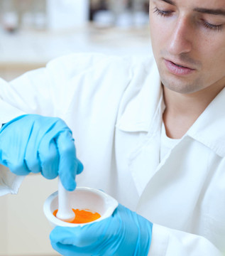 一個年輕的男性研究員用臼和杵均勻混合在一個實驗室工作的肖像