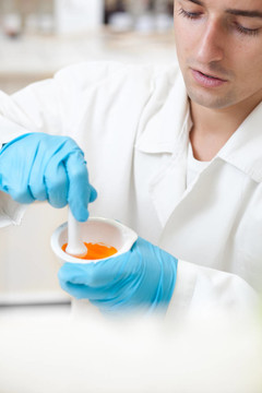 一個年輕的男性研究員用臼和杵均勻混合在一個實驗室工作的肖像