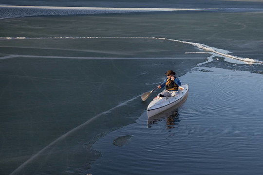 独木舟划桨在结冰的湖面
