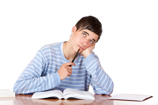 年輕的學生坐在桌子上打開的書看起來沉思。白色孤立。
