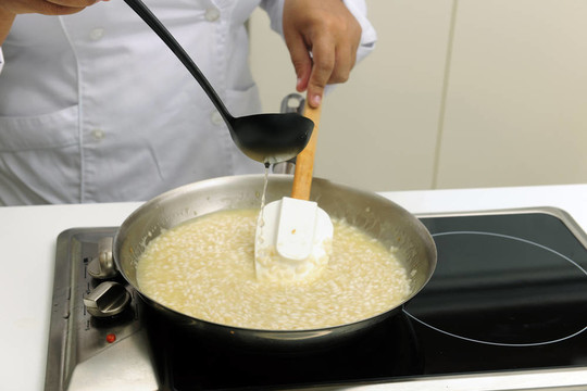 廚師烹飪燴飯加湯汁攪拌