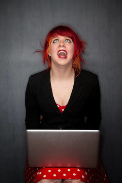 松软的红头发的女孩用一台笔记本电脑