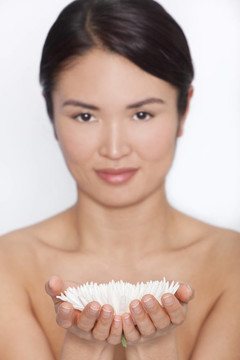 一位美麗的日本亞洲女子在一個美麗的SPA概念設置白色菊花的選擇性焦點工作室照片