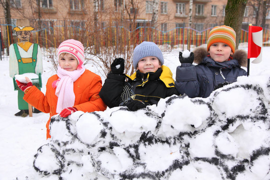 三個孩子在院子里打雪仗的雪堡壘的墻