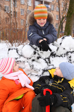 三個(gè)孩子在雪堡在院子里
