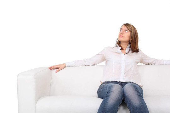 年輕漂亮的女人坐在白色的皮沙發(fā)上赤腳