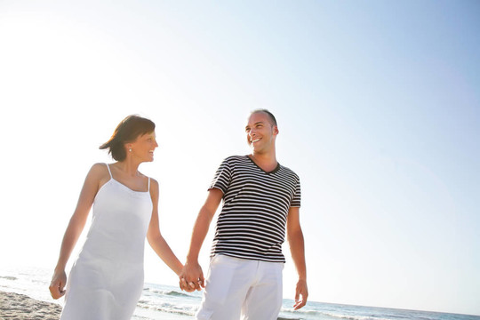 快乐的年轻夫妇在海滩上散步。