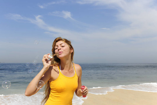 夏日樂趣：在海灘上吹肥皂泡的女人