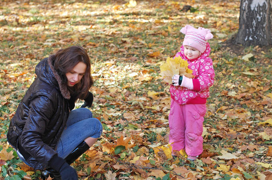 妈妈带着女儿在秋天公园散步