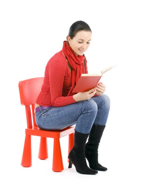 坐在紅色的；孩子的椅子年輕女子讀書(shū)