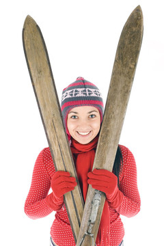 微笑的年輕女子在冬季帽持有舊木滑雪