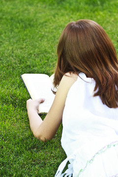 年輕漂亮的女孩在戶外看書