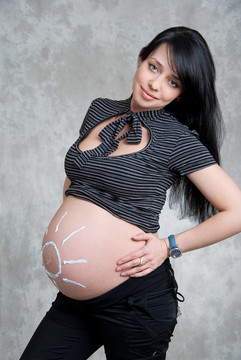 一個(gè)快樂的懷孕女孩，陽光畫在肚子上