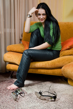 迷人的微笑女子放松和坐在沙發(fā)上在家里