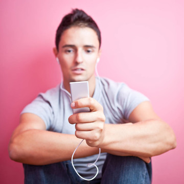 年輕英俊的男人在他的便攜式MP3播放器在自己的房間里聽音樂（顏色色調(diào)的圖像）