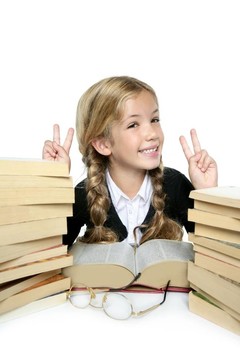 小學生金發(fā)編織女孩微笑與堆疊書籍