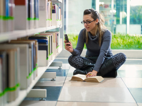 女孩短信與手機在圖書館