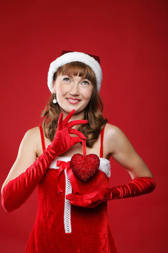 年輕迷人的女孩裝扮成圣誕老人，手里拿著一份禮物。