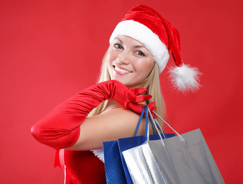 一個(gè)年輕迷人的女孩打扮成Santa與購物袋在他們手中的肖像