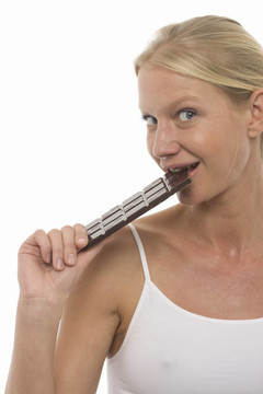 年輕美麗的白種女人吃一塊巧克力，看著鏡頭